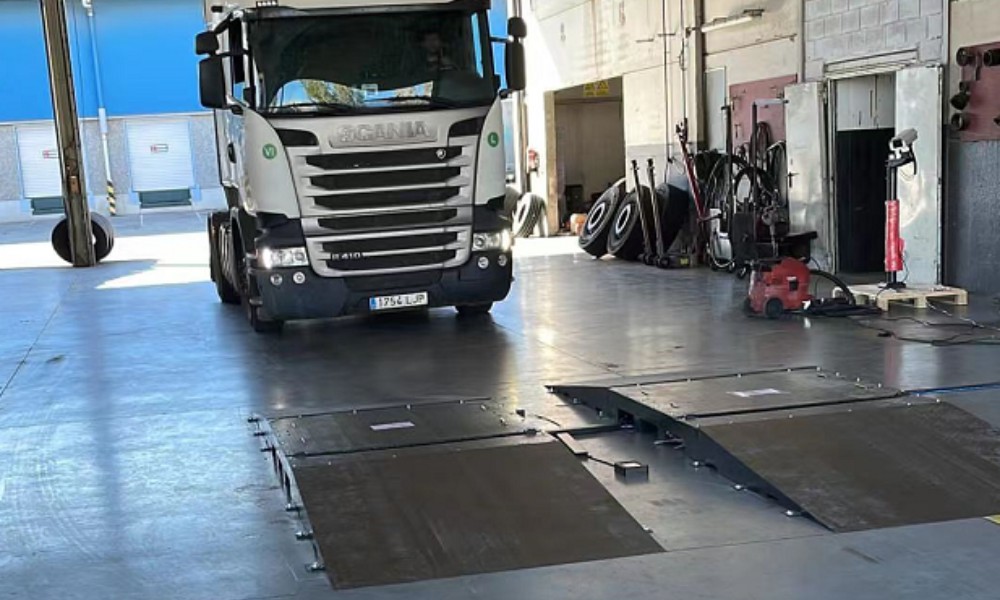 Commercial fleet vehicles approaching a drive-over tire inspection lane.