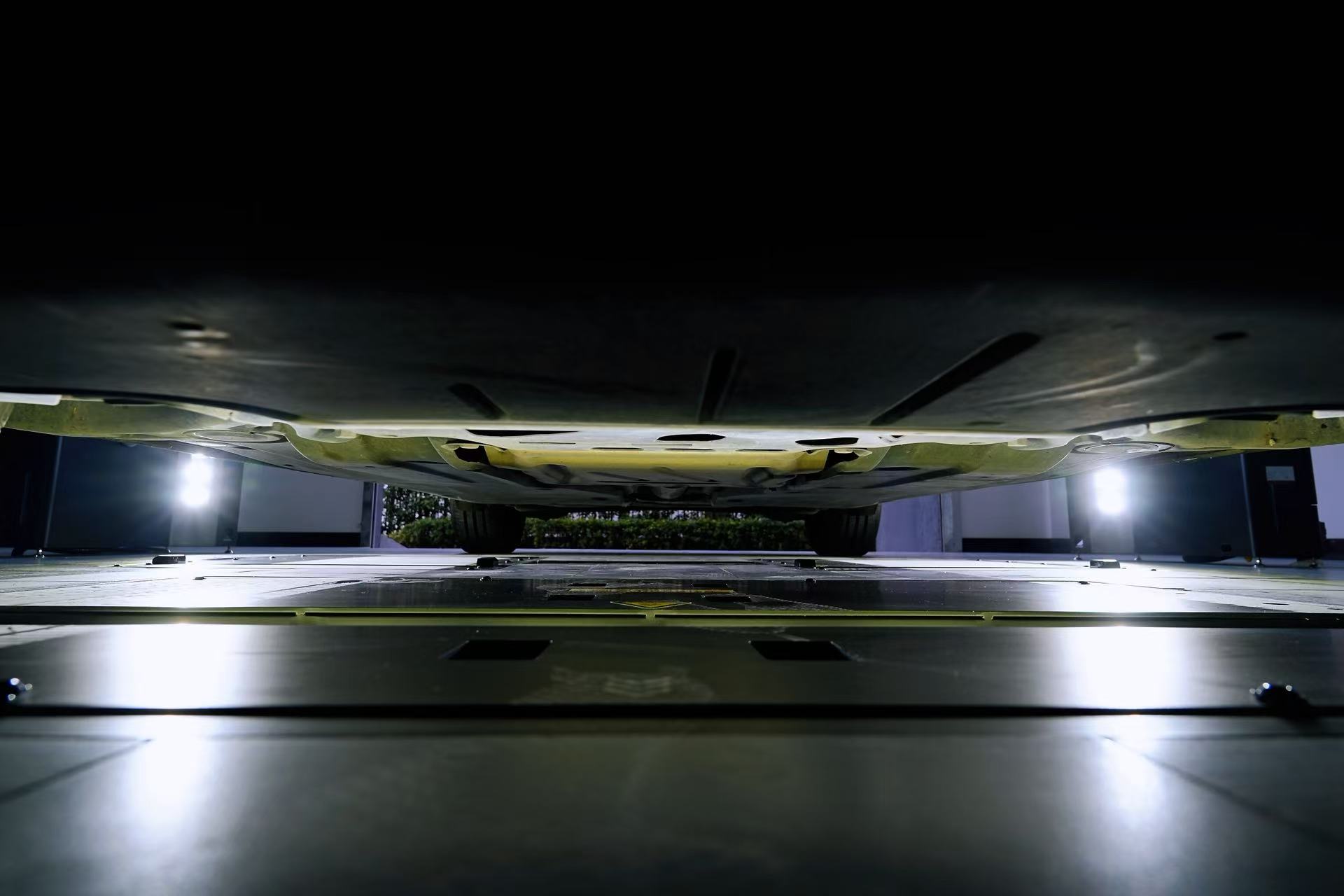 Vehicle underbody above an illuminated floor-mounted inspection scanner.