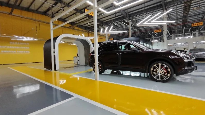 Black vehicle beside a white Elscope Vision inspection arch inside a facility