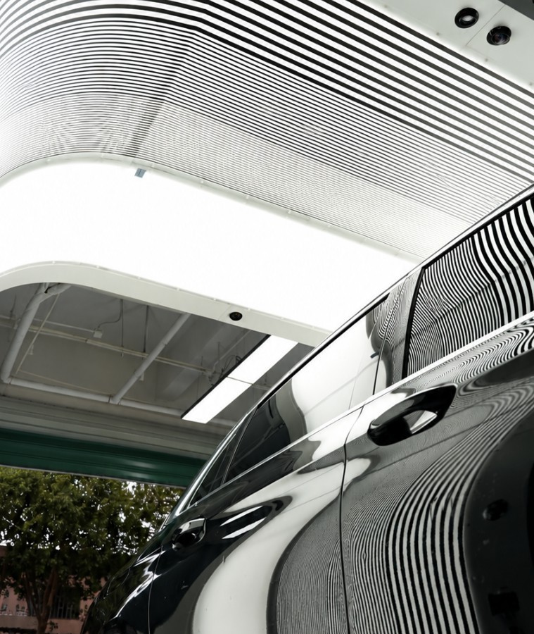 Striped light from an arch scanner reflecting along the doors of a black car