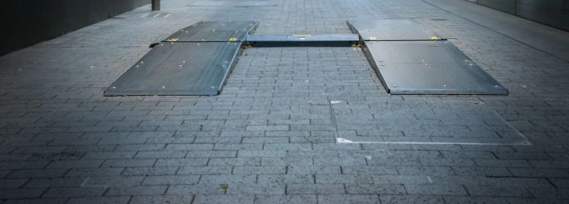 Drive-over tire tread scanner plates installed in a paved entrance lane