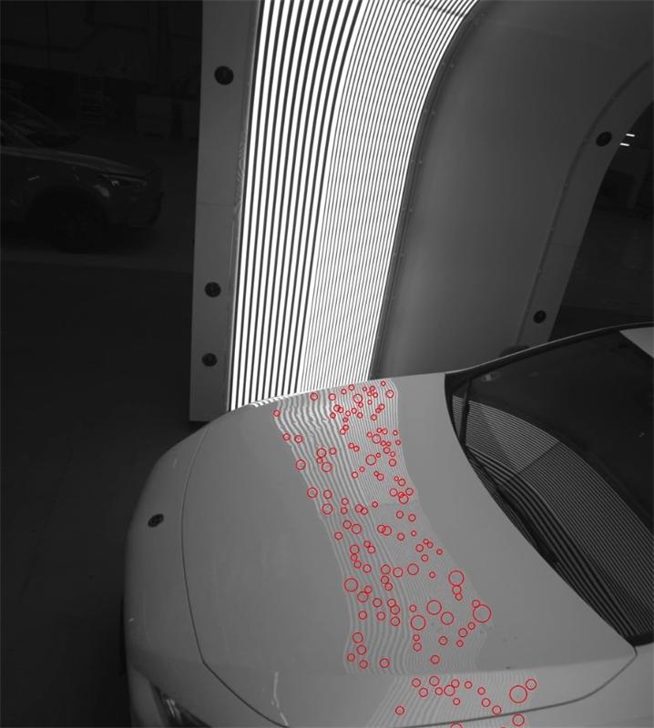 Grayscale image of a car hood under arch scanner light with many hail dents circled in red