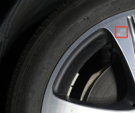 Close-up from a sidewall scan image showing the tire sidewall and an alloy wheel spoke, with a red box marking a spot on the wheel
